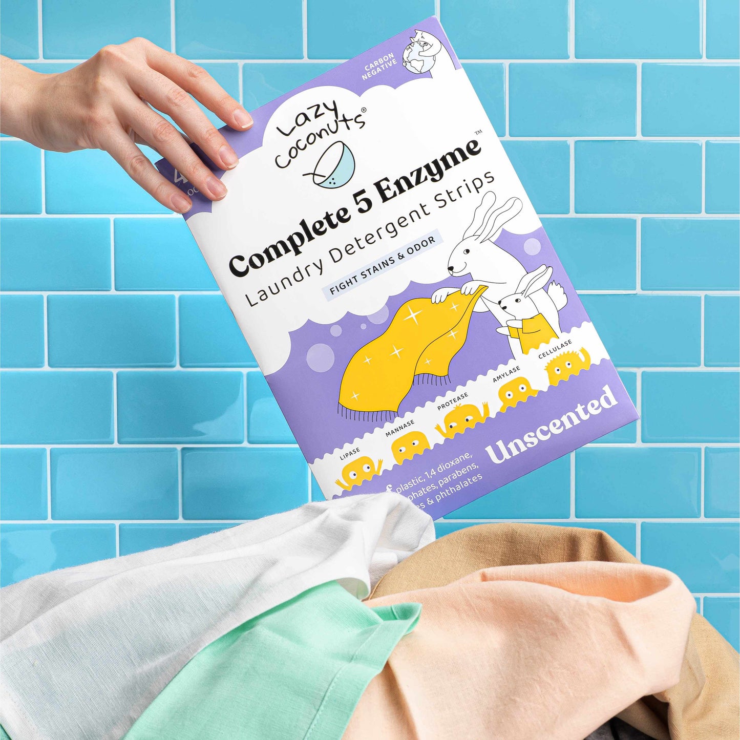 Lazy Coconuts laundry detergent strips packaging held by a hand against a blue tiled wall.