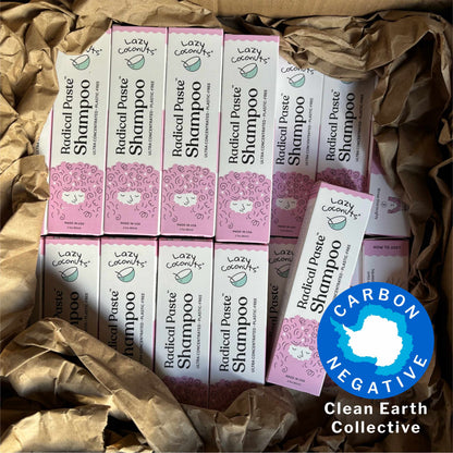 Several boxes of Lazy Coconuts Radical Paste Shampoo arranged in kraft shipping paper packaging, with a blue circular 'Carbon Negative' badge in the lower right corner.