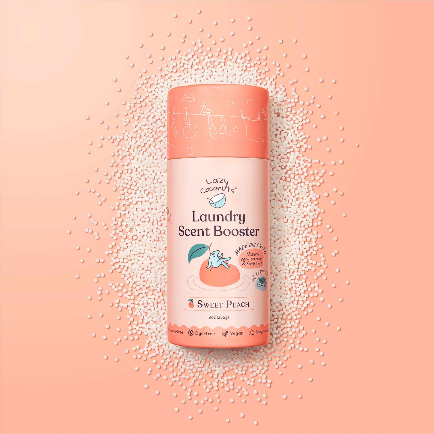 A bottle of Lazy Coconuts Laundry Scent Booster in Sweet Peach, surrounded by scattered white scent beads on a peach-pink background.