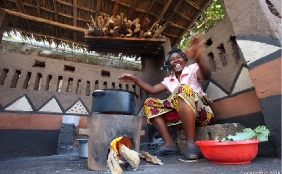 woman cooking with new efficient cookstove in Malawi, funded by Lazy Coconuts impact carbon offsets